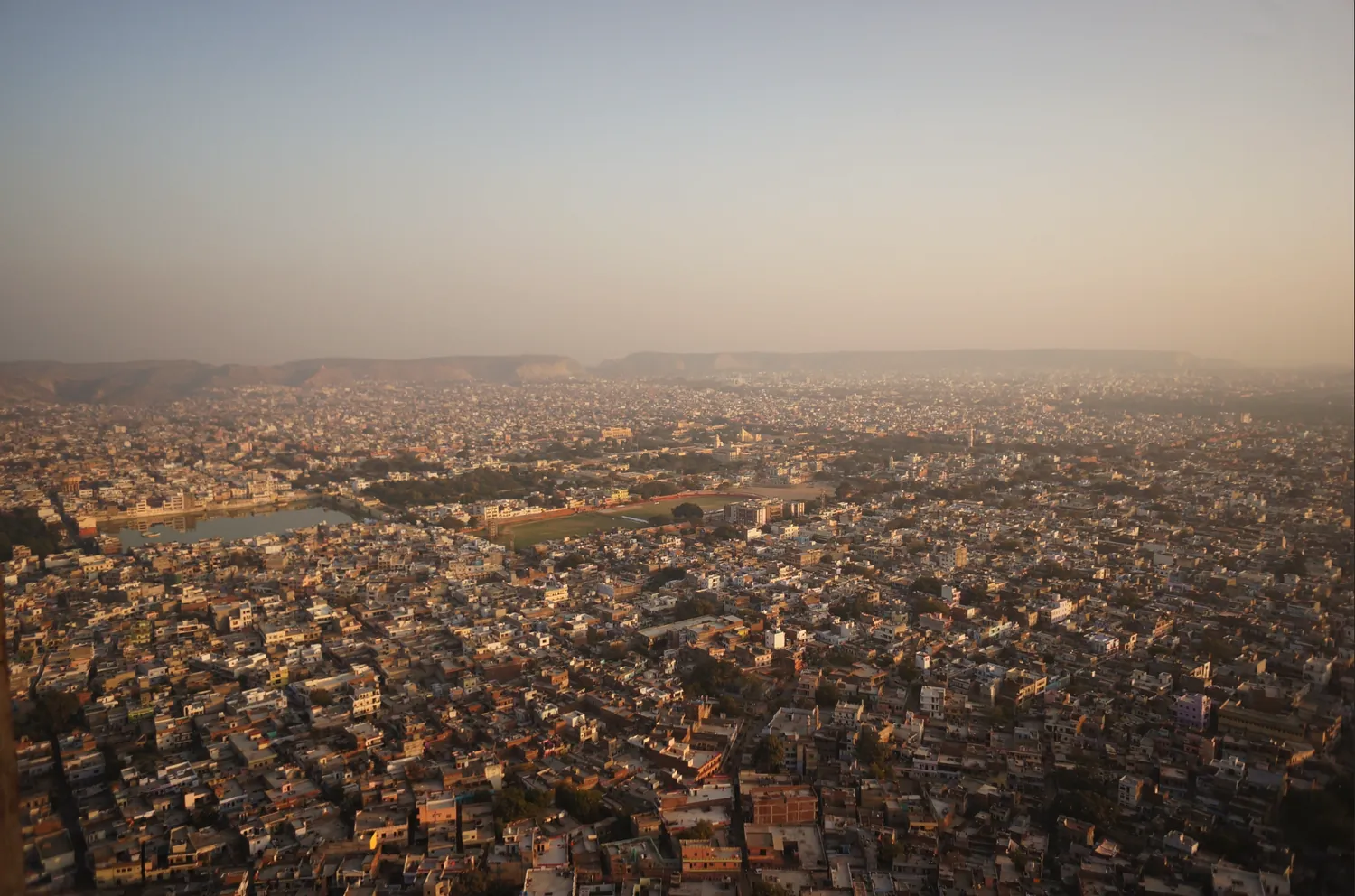 An Indian city spread across the plain, seen from a hillside in hazy evening light, used in the Just Go India guidebook to show the urban landscape.